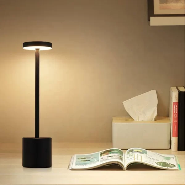 crna lampa na stolu pored otvorene knjige