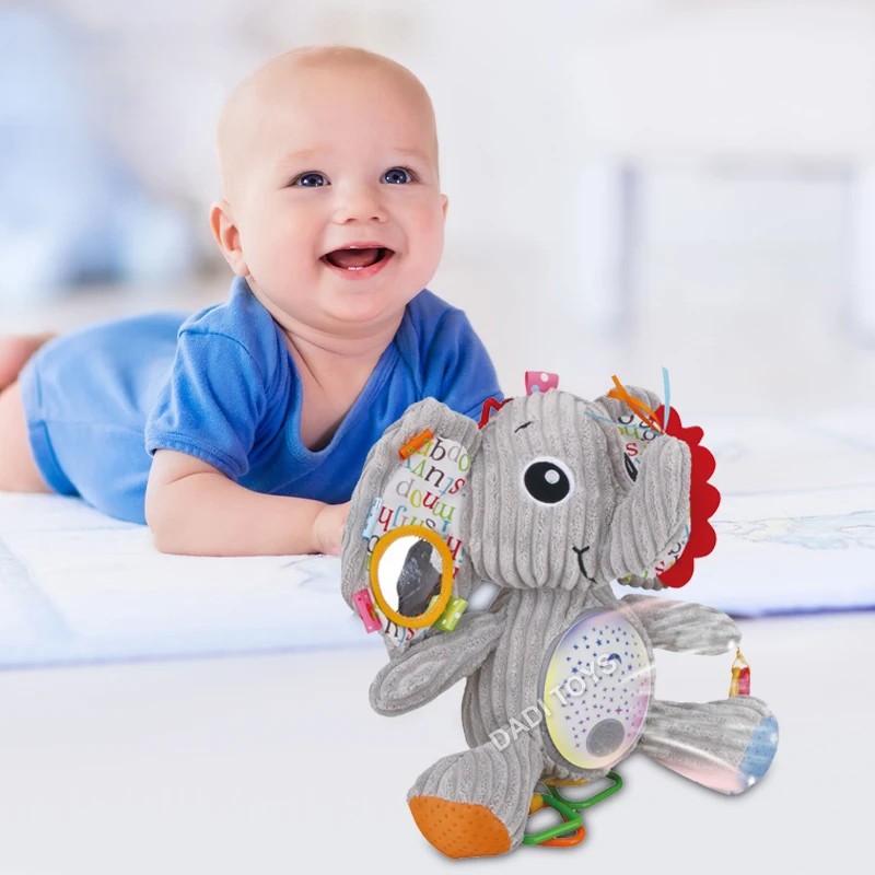 main-image-5 Mekana Umirujuća Slonče Igračka sive boje pored bebe na krevetu